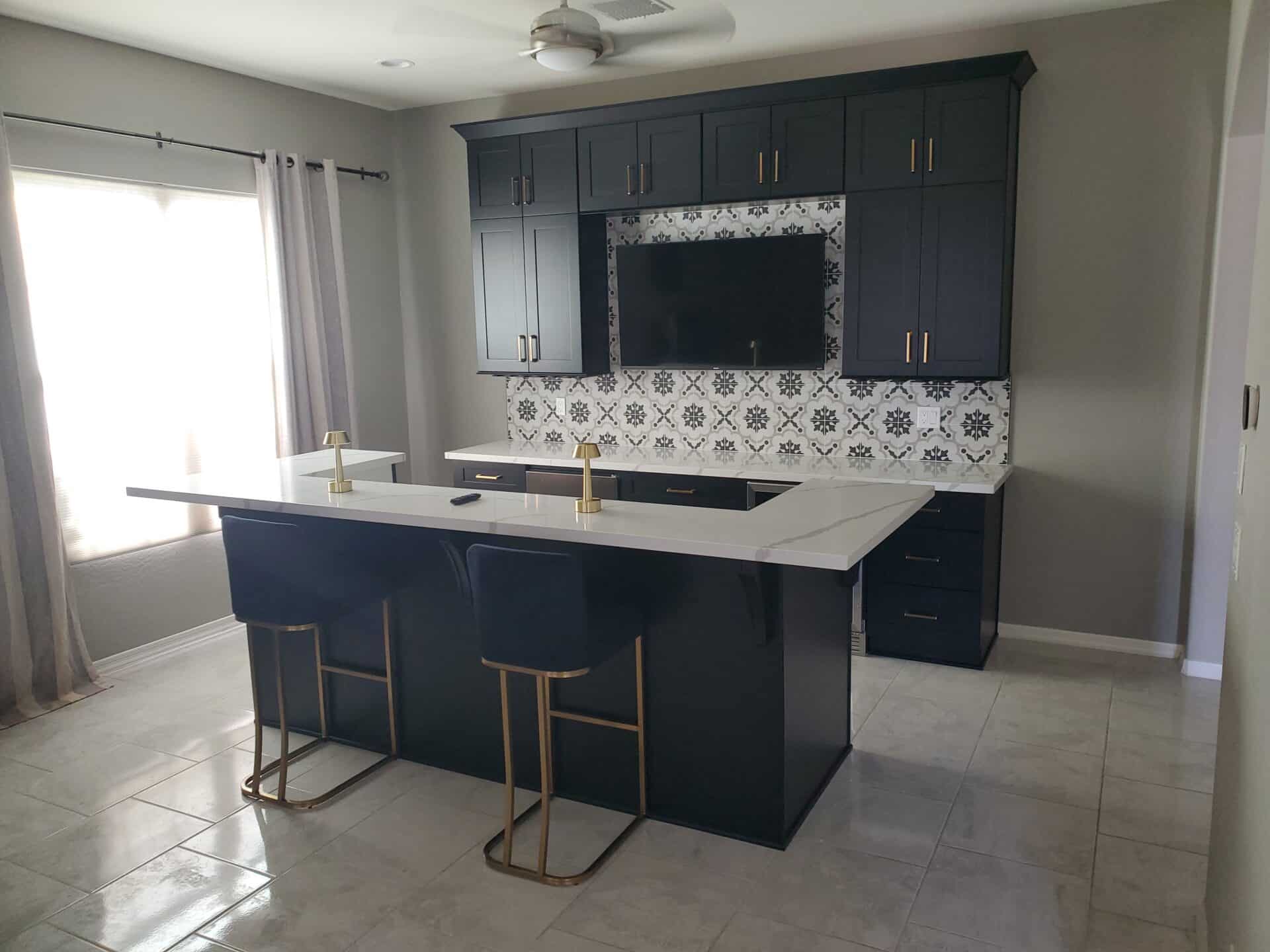 Custom navy dry bar with quartz countertops, brass hardware and a patterned tile backsplash