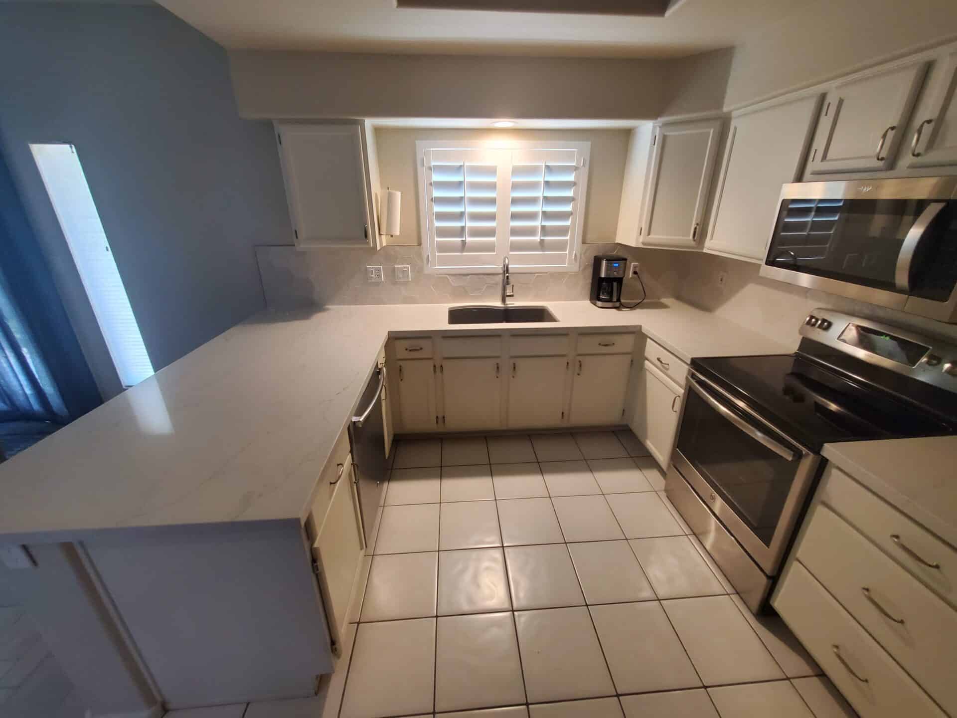 Ahwatukee kitchen with white quartz countertops, a hex tile backsplash and plantation shutters