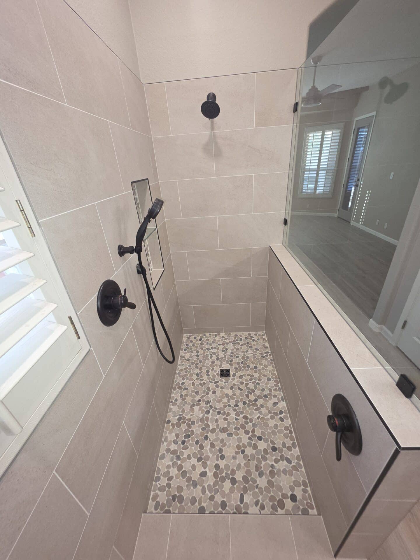 Curbless walk-in shower with a pebble tile floor and frameless glass