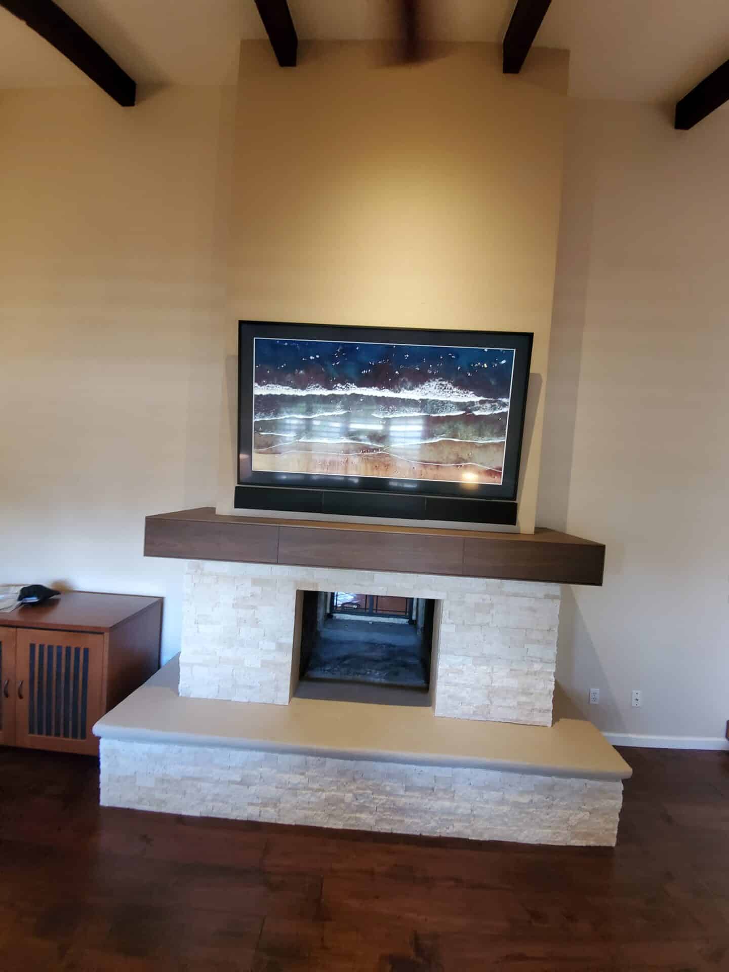 Remodeled fireplace with a stacked stone surround and a floating walnut mantel