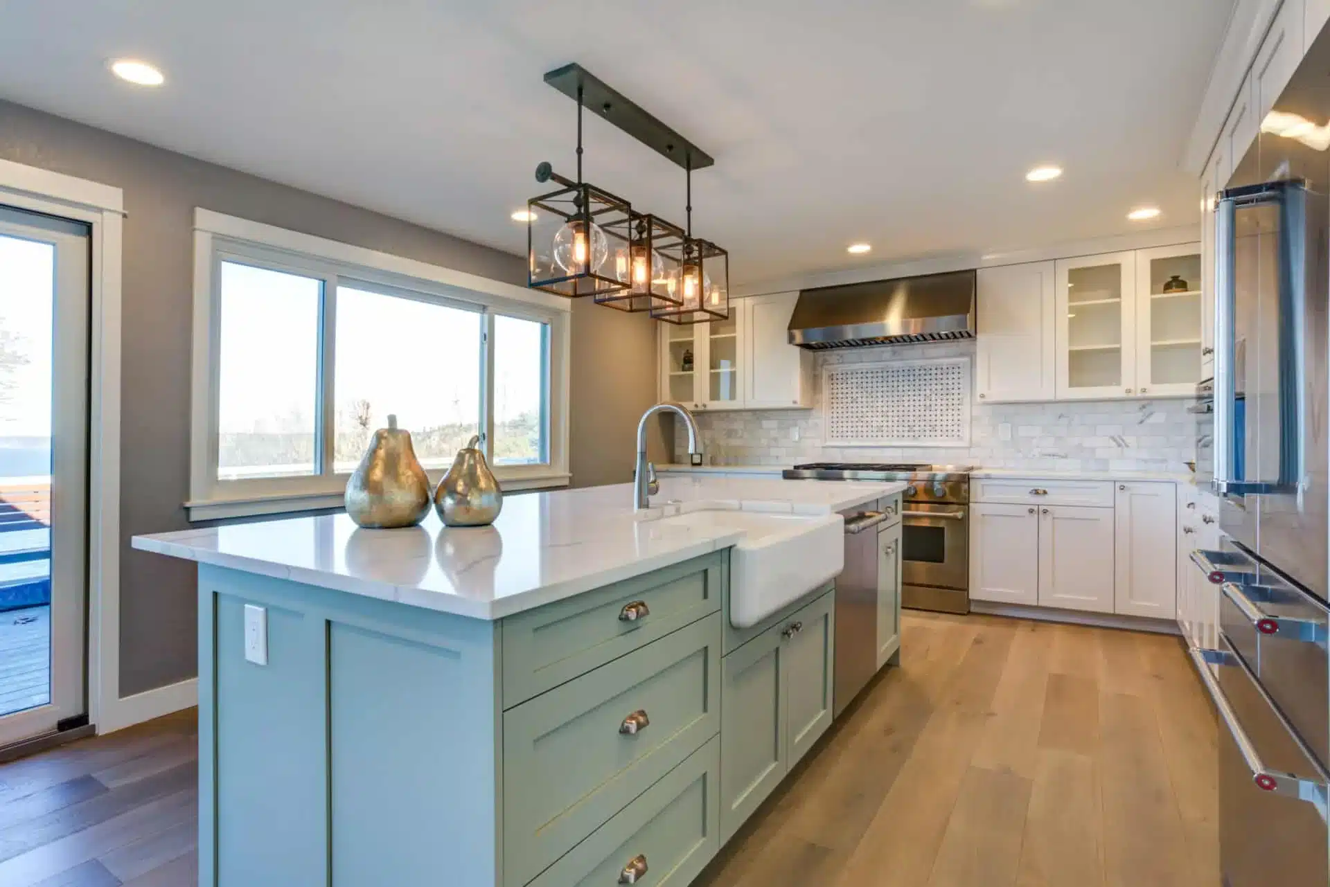 Finished kitchen with a sage green island, white cabinetry and quartz countertops