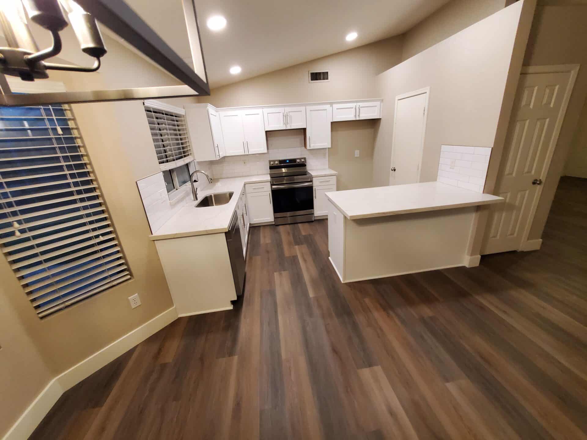 Gilbert kitchen after cabinet refacing, with white doors, quartz countertops and wood-look plank flooring